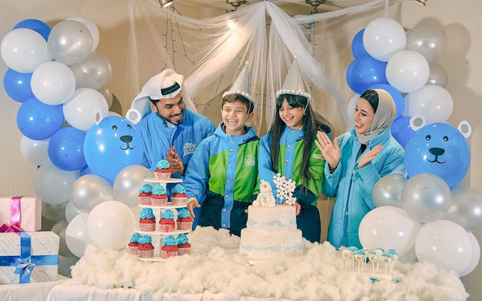 Family celebrating at Snow Dunes Theme Park with cupcakes and balloons.