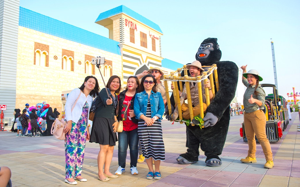 Visitors taking a selfie at Dubai Global Village with performers in costume.