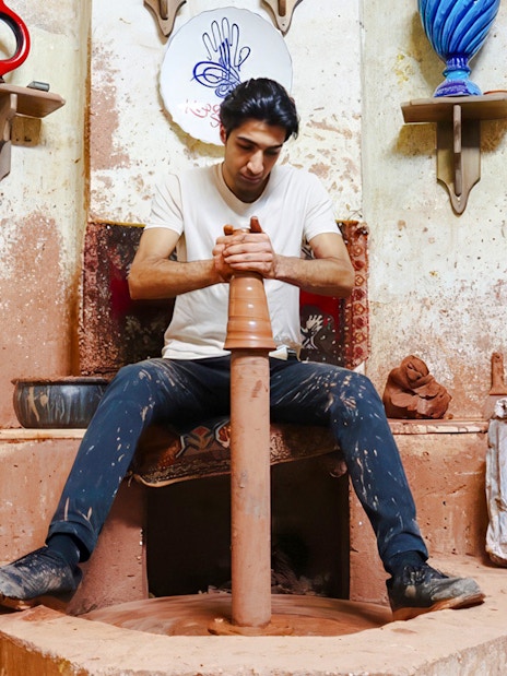Guest crafting pottery at Cappadocia workshop, surrounded by traditional ceramics.