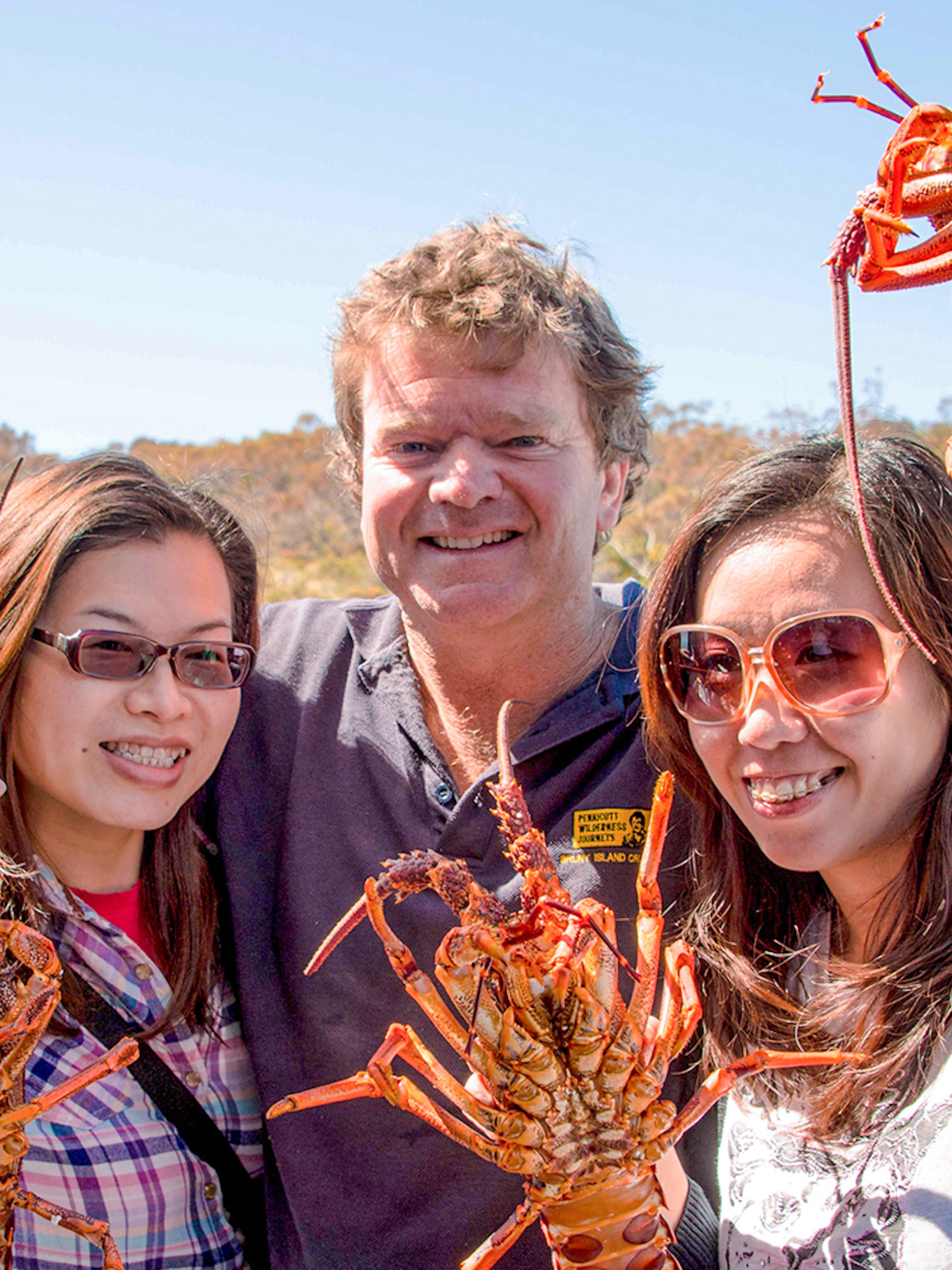 Tourists holding fresh lobsters on a Tasmanian Seafood Seduction tour.