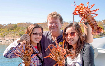 Tourists holding fresh lobsters on a Tasmanian Seafood Seduction tour.