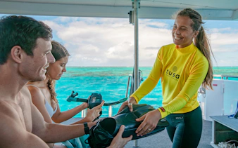 Snorkeling guide handing equipment to tourists on a boat near Cairns.