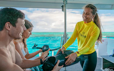 Snorkeling guide handing equipment to tourists on a boat near Cairns.