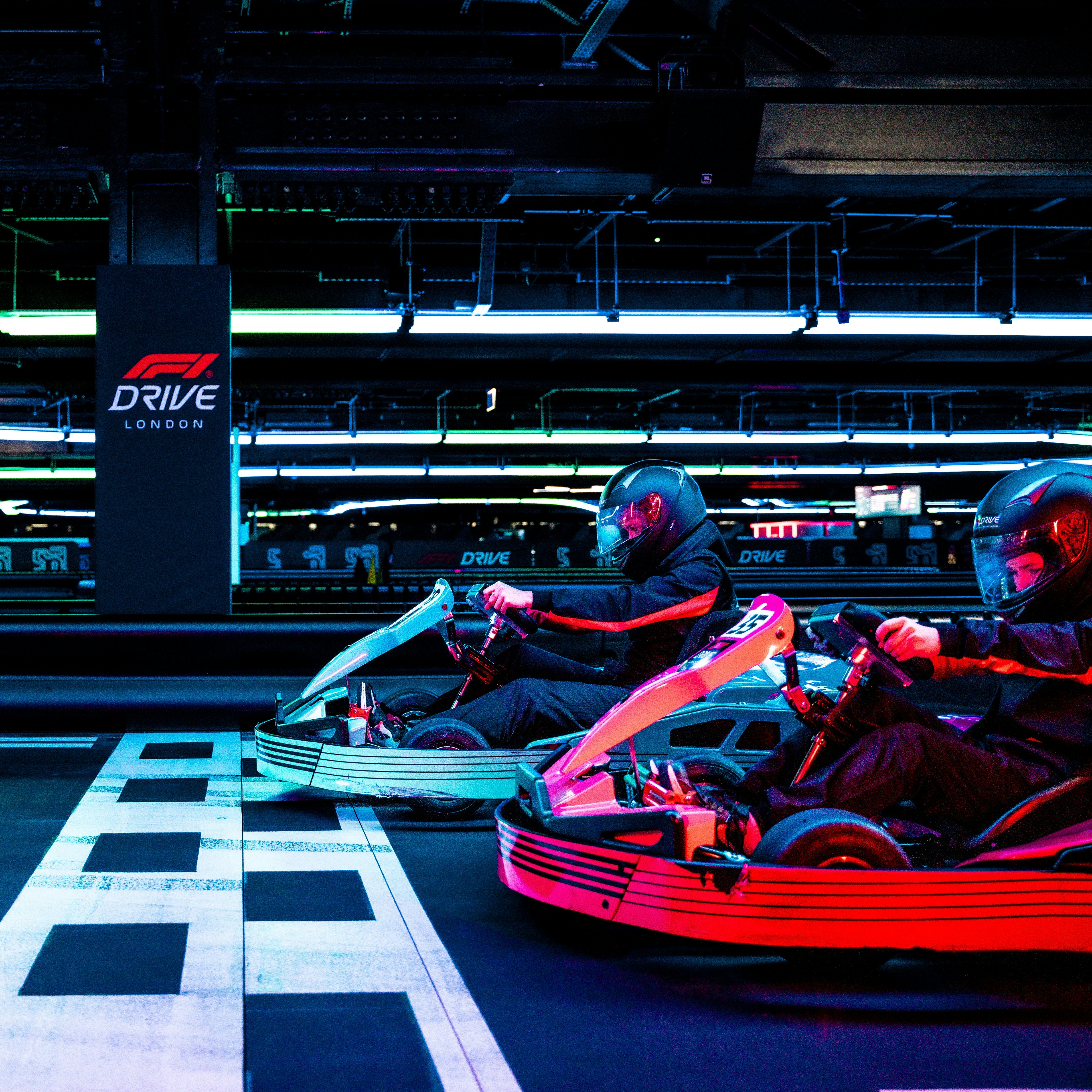 Go-kart race at indoor track in London with neon lighting.