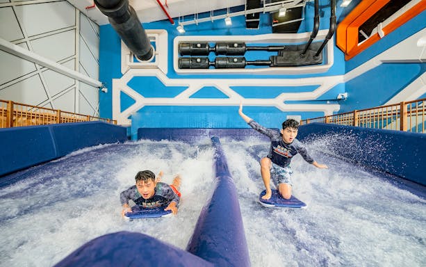 Visitors try surfing indoors at the Macau Studio City Water Park