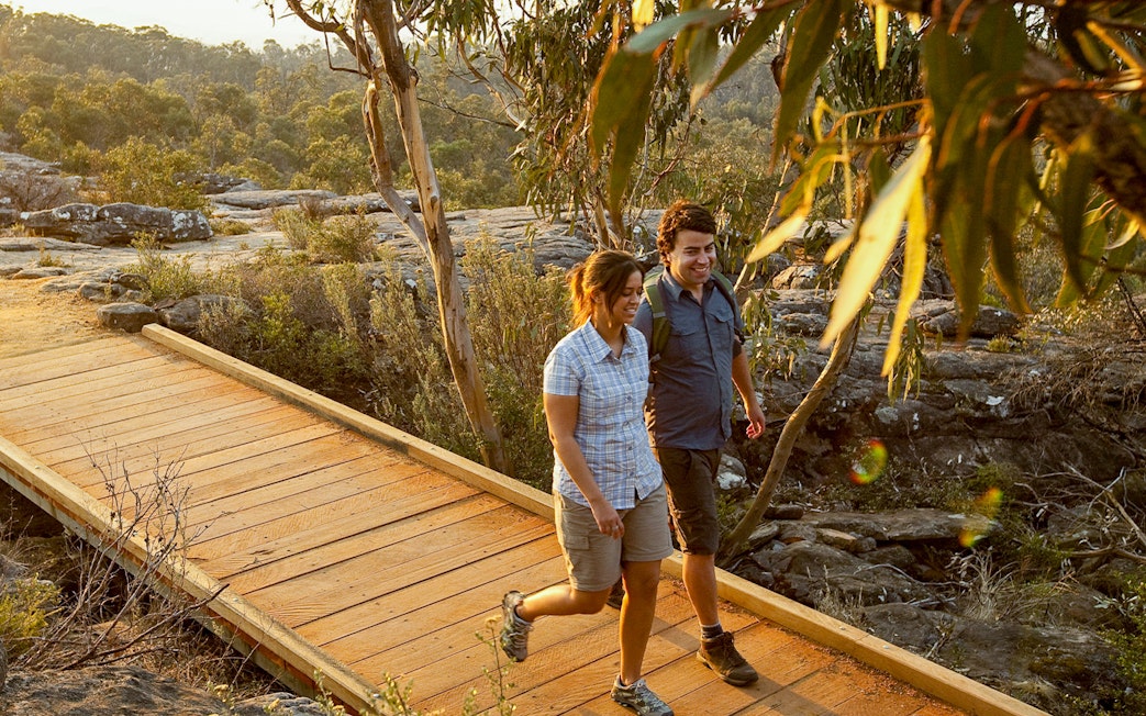 Couple walking on a wooden path in Grampians National Park during a guided eco tour from Melbourne.