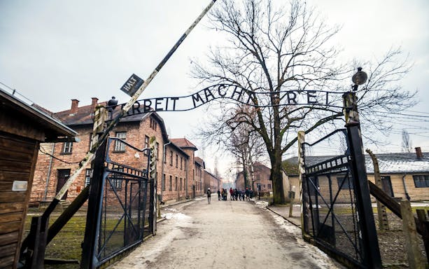 Entrance gate to Auschwitz concentration camp with visitors in the background.