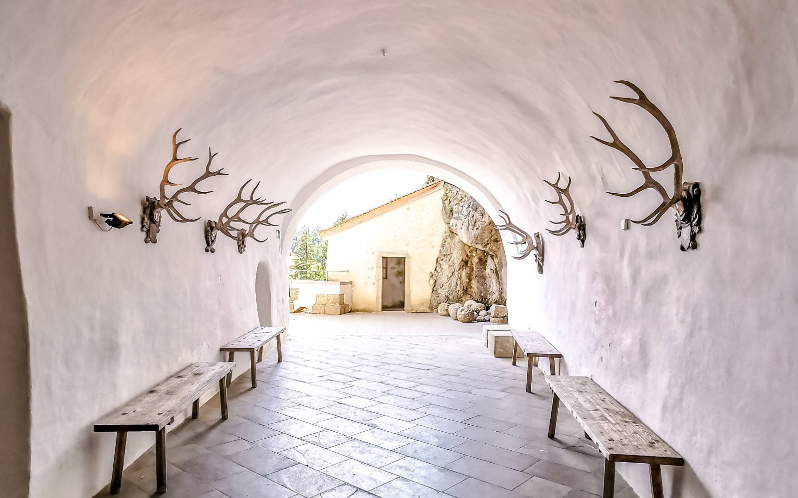 Interior corridor of Predjama Castle with antler decorations and wooden benches.