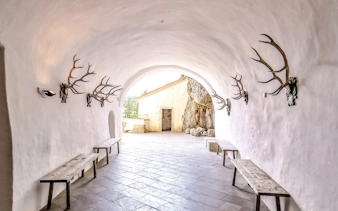 Interior corridor of Predjama Castle with antler decorations and wooden benches.