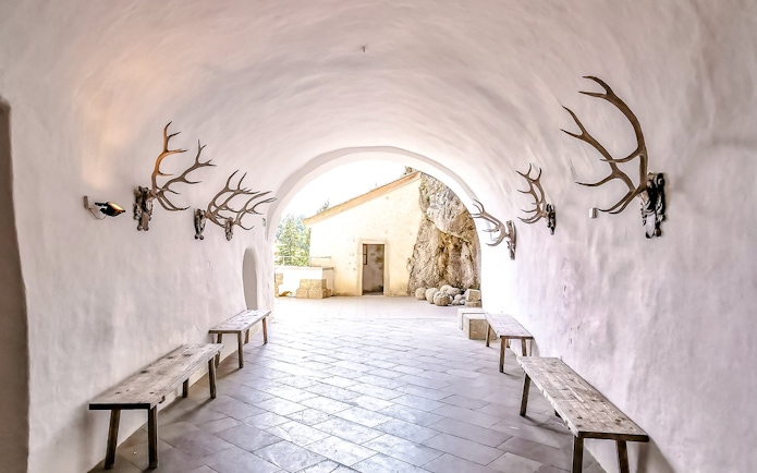 Interior corridor of Predjama Castle with antler decorations and wooden benches.