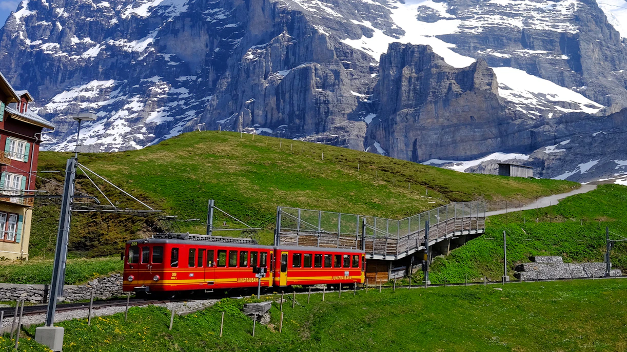Red train on Jungfraubahn railway with snow-capped mountains in Jungfraujoch, Switzerland.