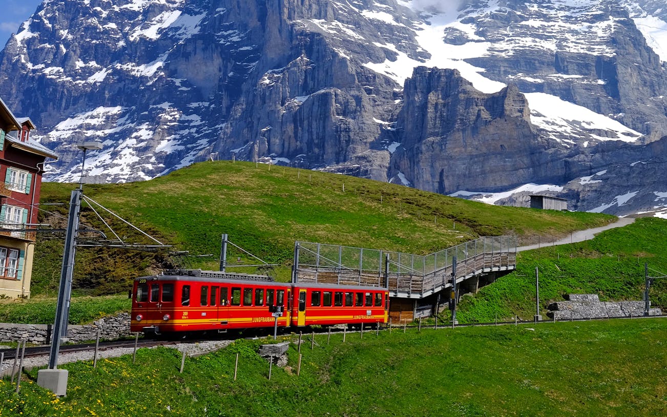 Red train on Jungfraubahn railway with snow-capped mountains in Jungfraujoch, Switzerland.