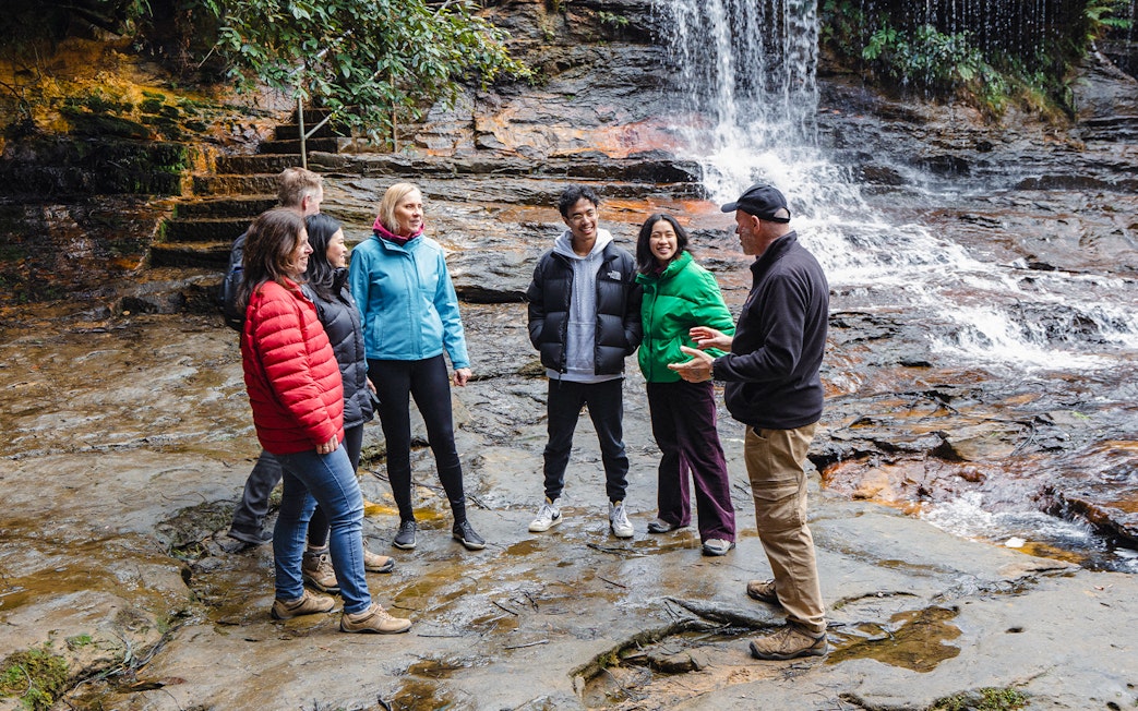 Guide with group near waterfalls in Blue Mountains.