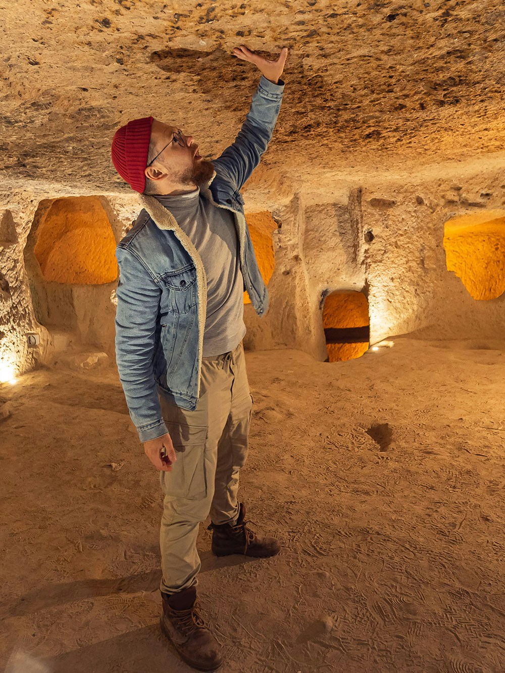Visitor exploring Kaymakli Underground City, examining ancient stone ceiling.