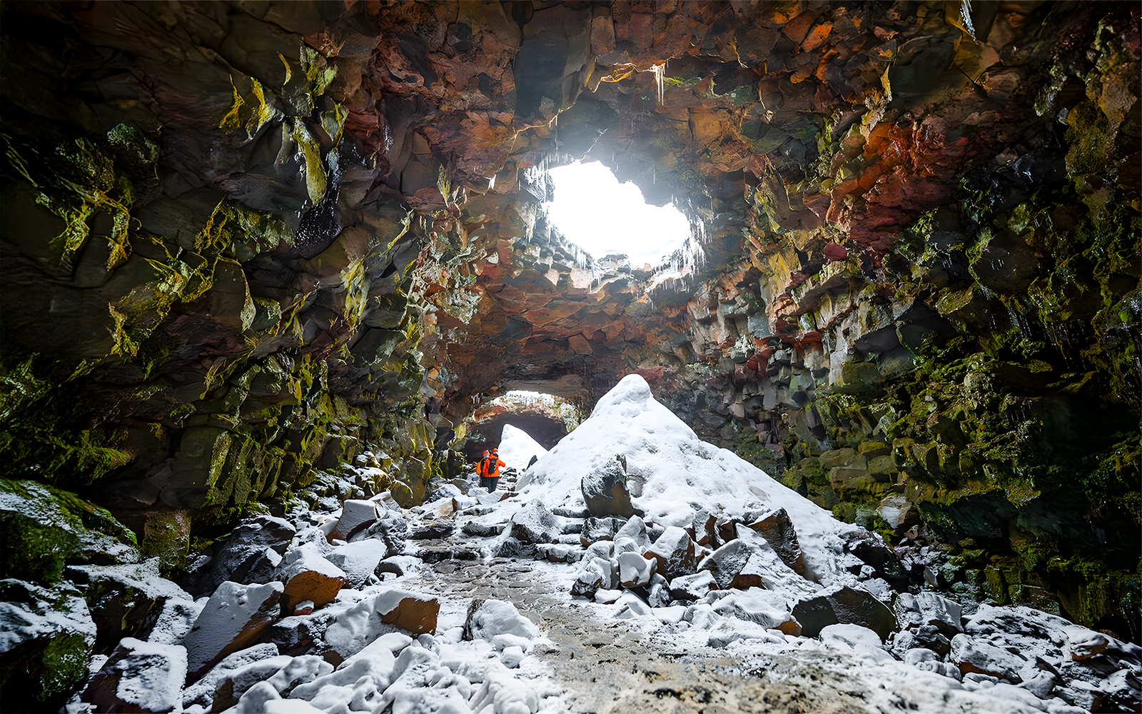 Guests exploring snow-covered Raufarhólshellir Lava Cave, Iceland.