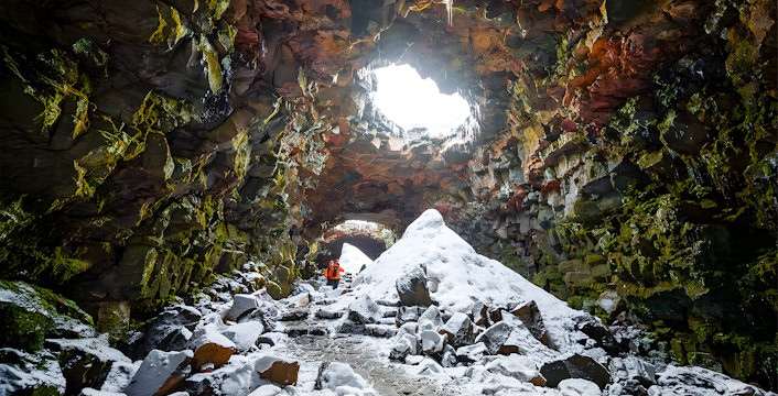 Guests exploring snow-covered Raufarhólshellir Lava Cave, Iceland.