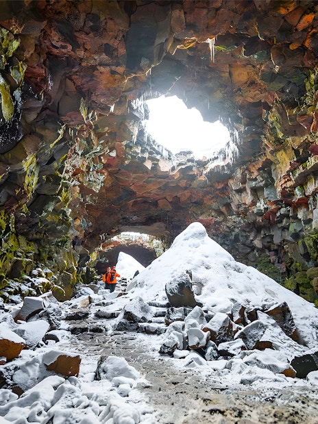Guests exploring snow-covered Raufarhólshellir Lava Cave, Iceland.
