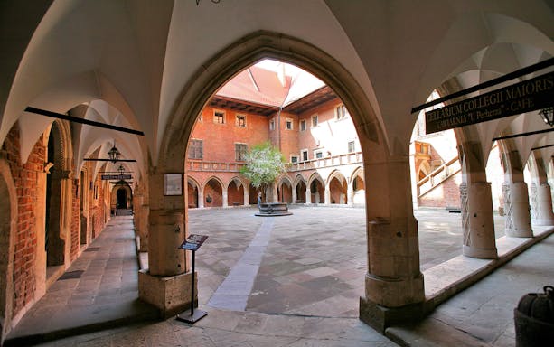 Courtyard of Collegium Maius, Krakow, with arched walkways and central tree.