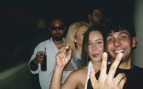 Group enjoying Barcelona nightlife at a club, smiling and holding drinks.
