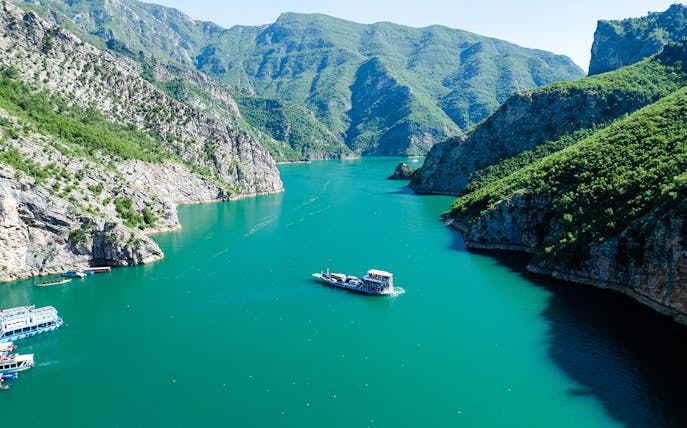 Aerial view of Komani Lake with boat navigating between mountains in Shkoder, northern Albania.