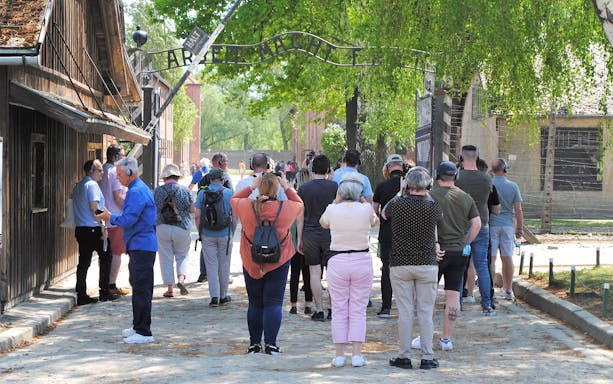 Tourists using audio guides at Auschwitz-Birkenau entrance, Poland.