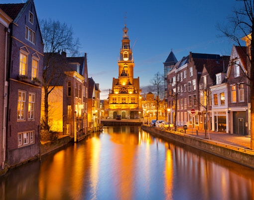 Canal view of Alkmaar, The Netherlands at night with illuminated buildings and historic tower.