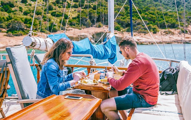 Couple dining on a boat during Athens sunset dinner cruise with scenic view.