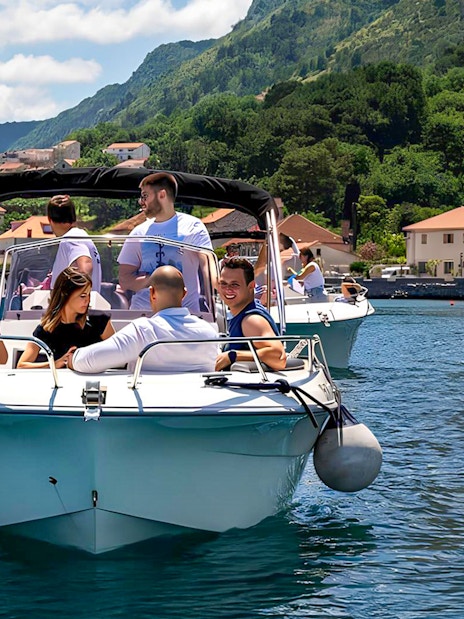 Guests on a speedboat tour near Blue Caves, with coastal village and mountains in the background.