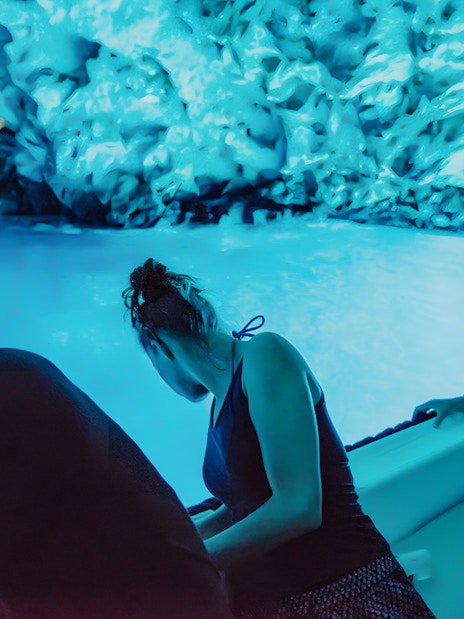 Tourists on a boat inside the illuminated Blue Cave during Blue Lagoon and 5 Islands tour.