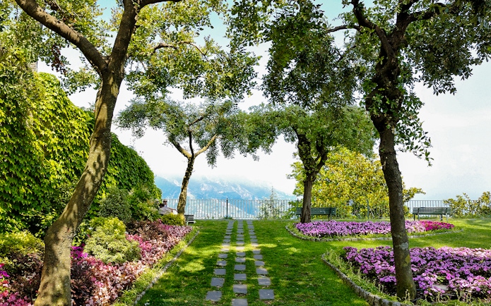 Garden path with flowers and trees at Principessa di Piemonte, overlooking the Amalfi Coast, Ravello, Italy.