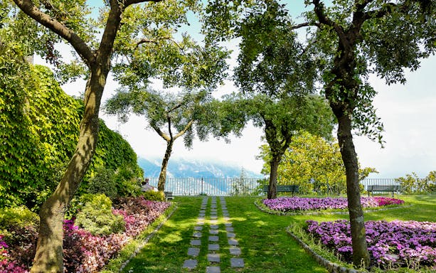 Garden path with flowers and trees at Principessa di Piemonte, overlooking the Amalfi Coast, Ravello, Italy.