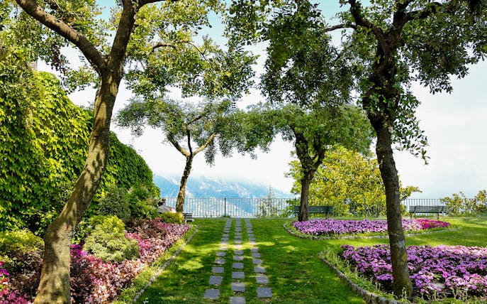 Garden path with flowers and trees at Principessa di Piemonte, overlooking the Amalfi Coast, Ravello, Italy.