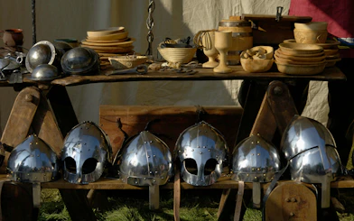 Medieval helmets and wooden bowls displayed at Battle Abbey reenactment.