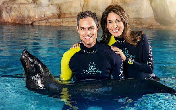 Couple interacting with sea lion at Aquaventure Waterpark, Dubai.