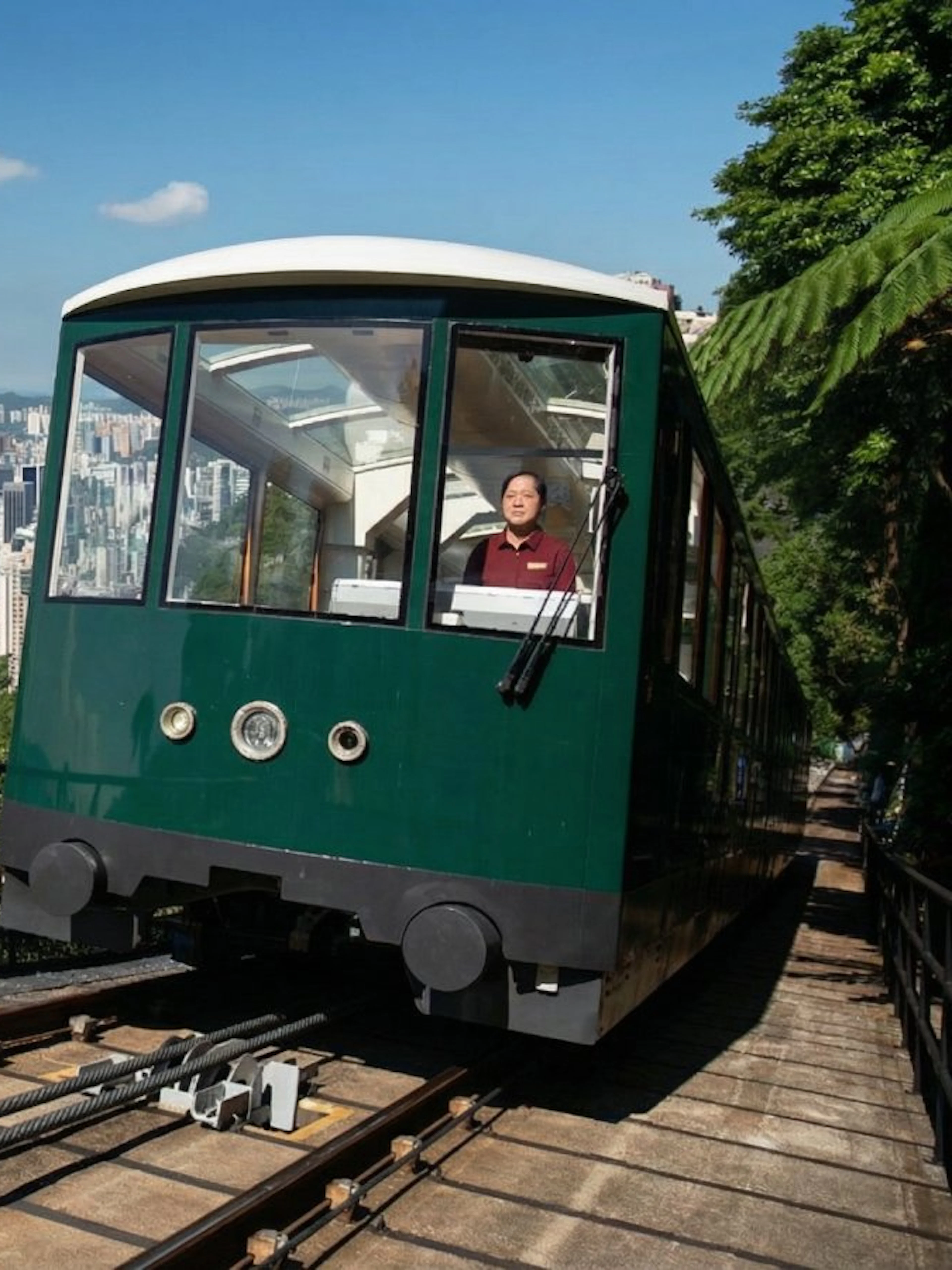 Peak Tram ascending with Hong Kong skyline in the background.