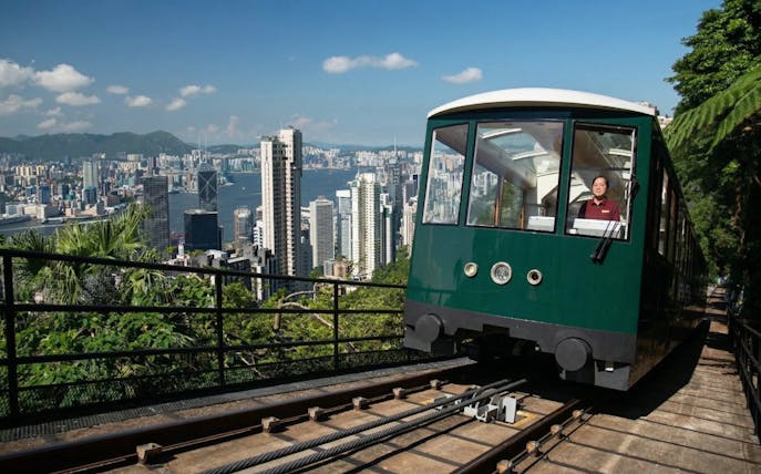 Peak Tram ascending with Hong Kong skyline in the background.