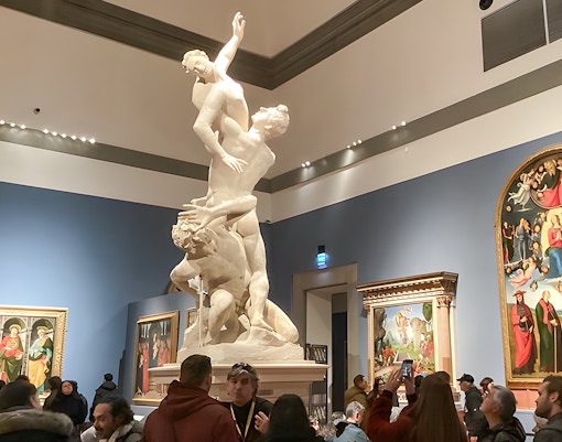 David statue in Accademia Gallery, Florence, with visitors viewing art on timed entry tickets.