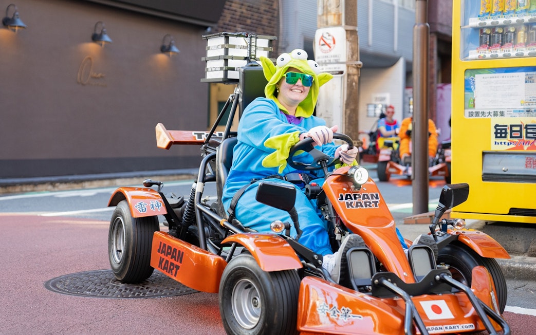Woman in costume driving a go-kart on Shibuya Shinjuku Tour, Tokyo.