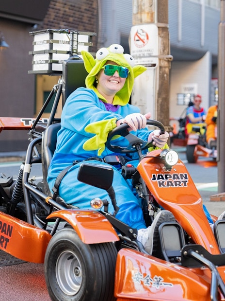 Woman in costume driving a go-kart on Shibuya Shinjuku Tour, Tokyo.