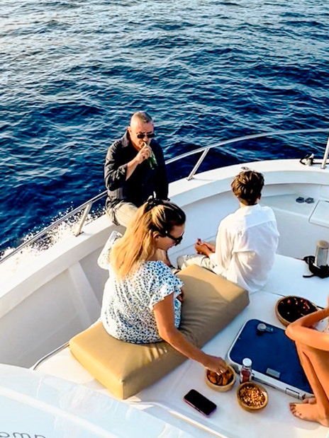 Tourists enjoying snacks and drinks on a boat during a sunset cruise in Gran Canaria.