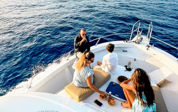 Tourists enjoying snacks and drinks on a boat during a sunset cruise in Gran Canaria.