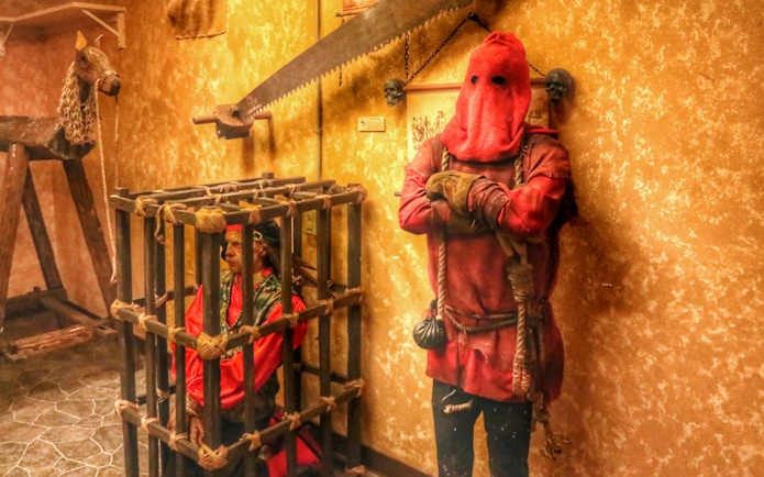 Medieval Torture Museum exhibit with a figure in a cage and a hooded figure nearby.