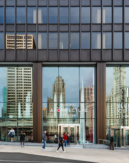 Chicago Architecture Center facade with city reflections and pedestrians.