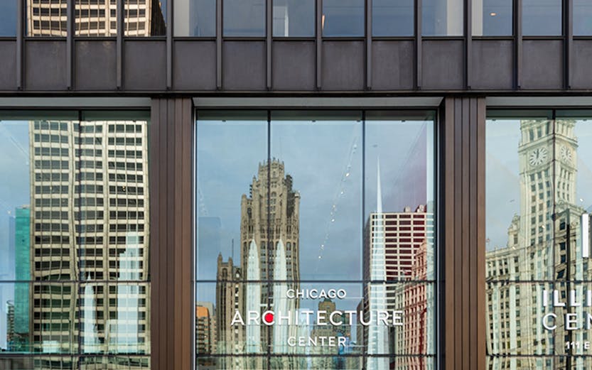 Chicago Architecture Center facade with city reflections and pedestrians.