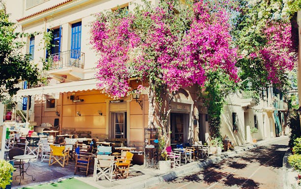 Outdoor cafe with colorful chairs and bougainvillea in Athens, Greece, on a street food tour route.