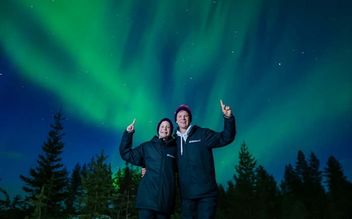 Couple enjoying Northern Lights in Rovaniemi, Finland.