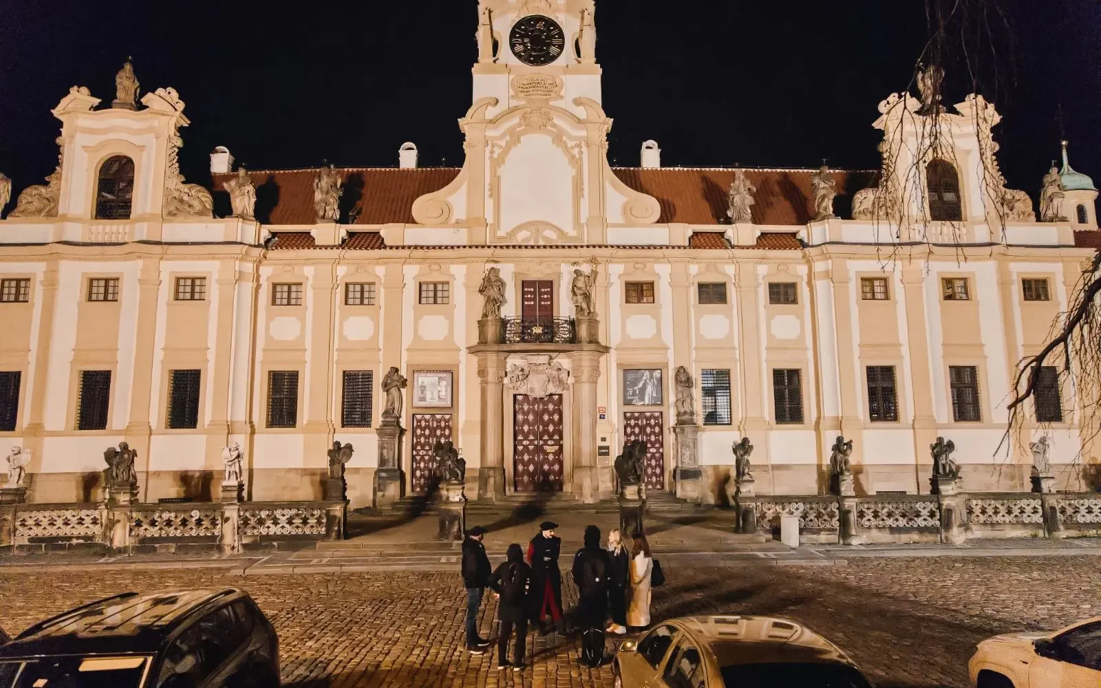 Group of tourists outside Prague Castle at night during guided tour.
