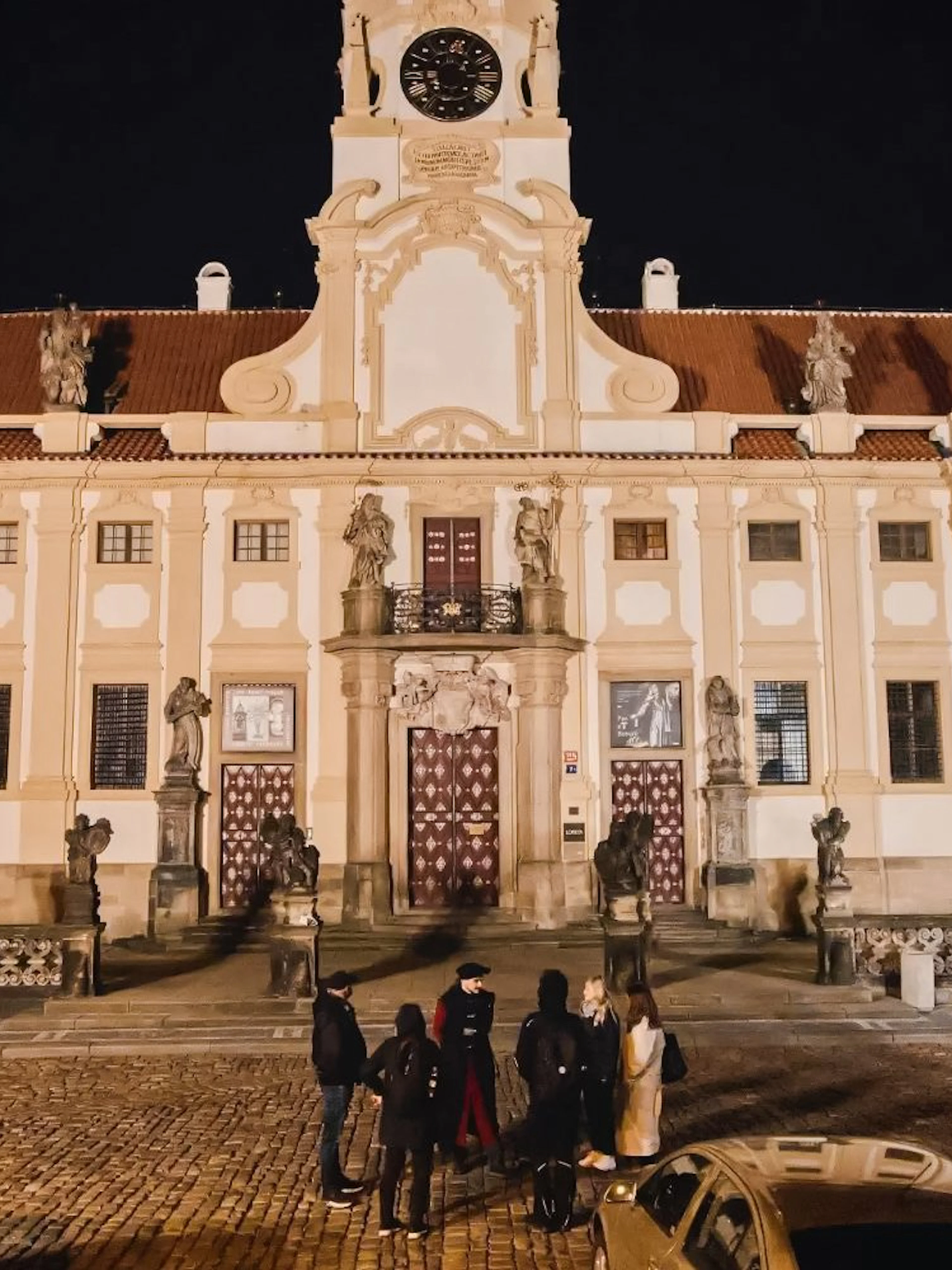 Group of tourists outside Prague Castle at night during guided tour.