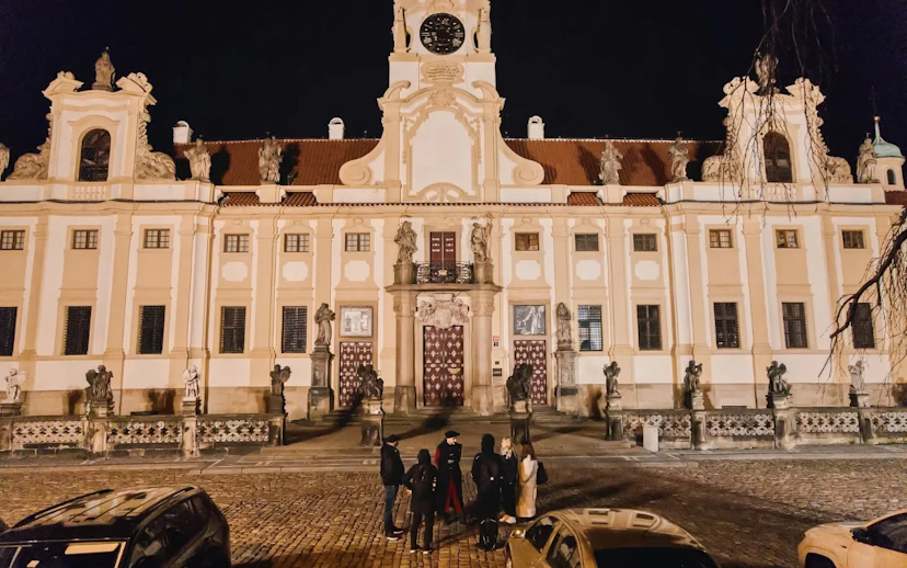 Group of tourists outside Prague Castle at night during guided tour.