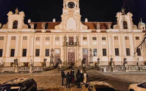 Group of tourists outside Prague Castle at night during guided tour.